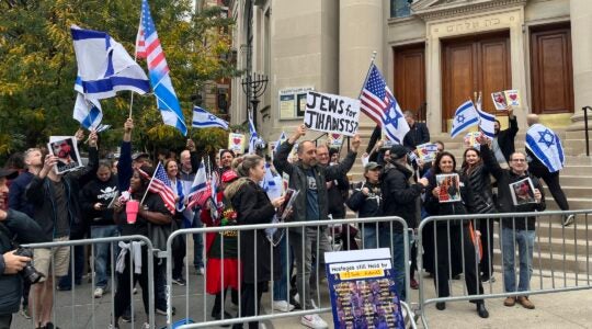 Protesters wave Israeli flags behind a barricade in front of the synagogue building.