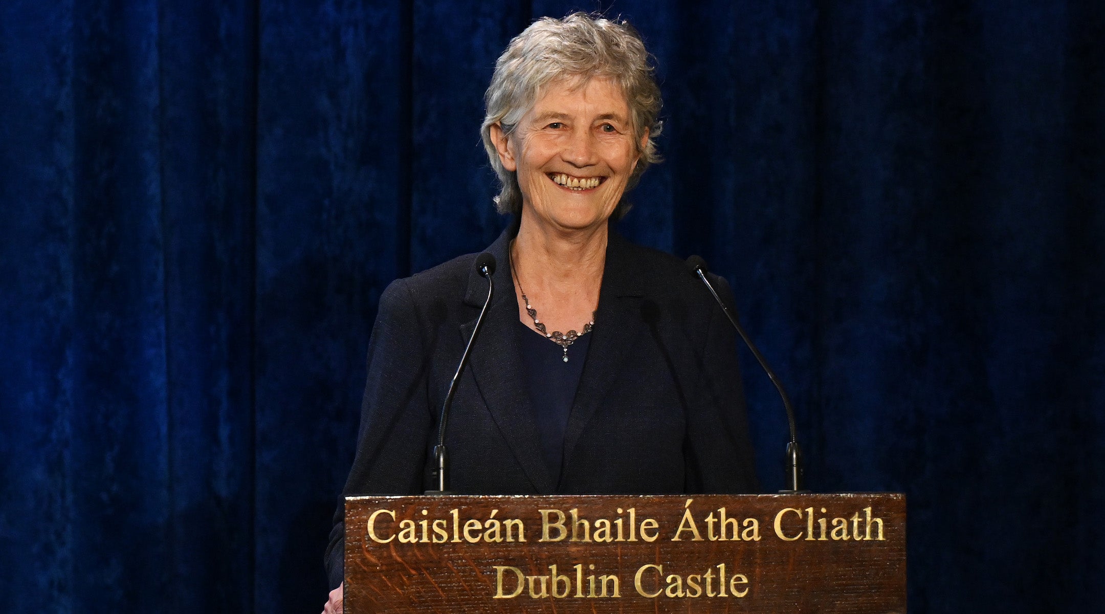 A photo of Connolly speaking from a podium and smiling.