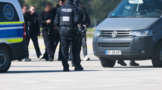 A photo of German police leading the accused. His face is blurred.
