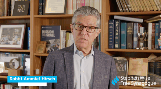 A photo of Hirsch speaking in front of a book shelf.