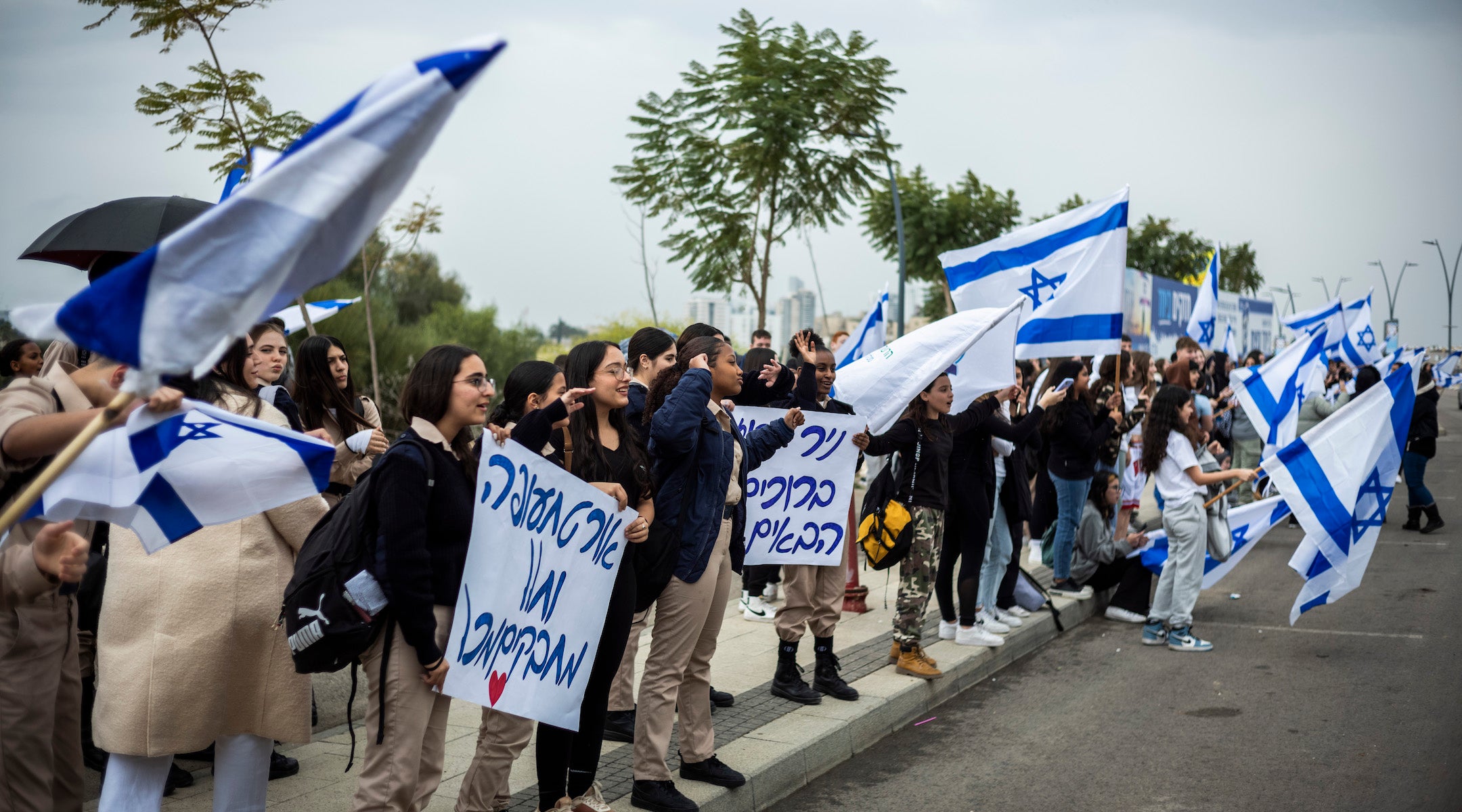 A photo of children waving israeli flags by a road.