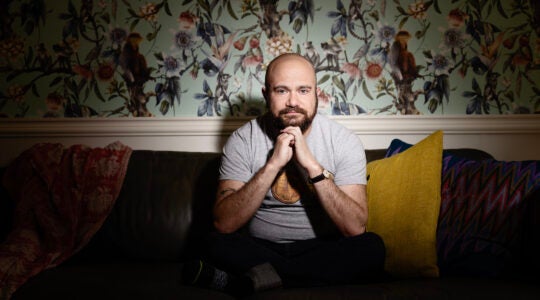A photo of Lukoff sitting on a couch with his hands folded under his chin.