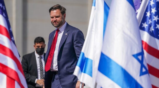 A photo of JD Vance walking between Israeli and American flags.
